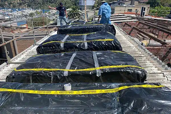 Asbestos removal in Perth with roofing materials safely wrapped and sealed in plastic on a residential roof during licensed removal process