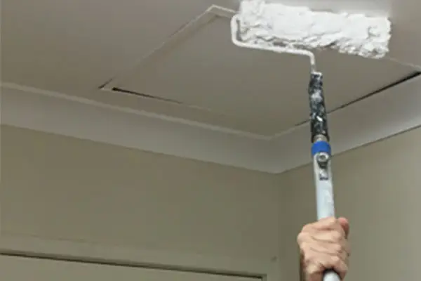 Ceiling patch repair and repainting in progress using a roller to restore a smooth finish on a residential ceiling in Perth