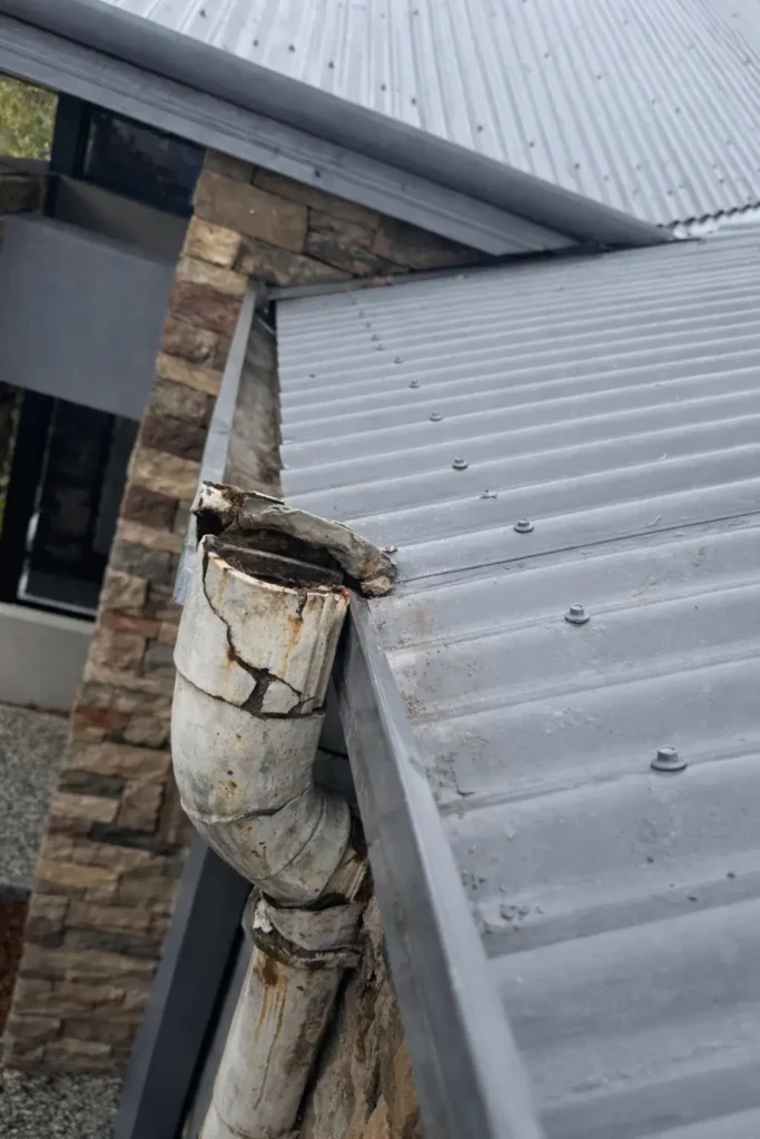 Damaged and rusted downpipe at roof gutter corner showing cracks and corrosion requiring downpipe replacement Perth service