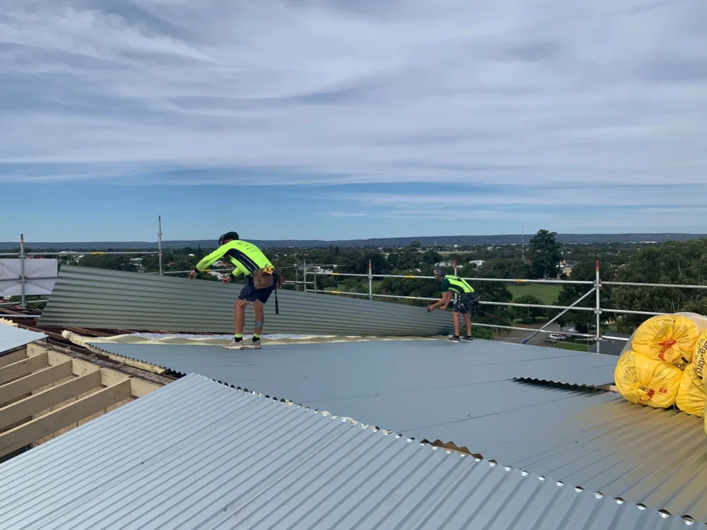 Insulmate roofers installing metal roofing sheets on a residential property in Perth with scaffolding and safety gear