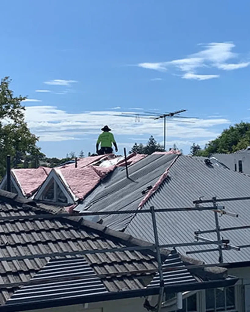 Roof replacement installation in Perth with roofing contractor working on new metal roof and insulation on residential home