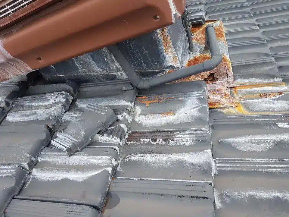 Damaged roof tiles with visible leak points and rusted flashing around roof penetration on a Perth home