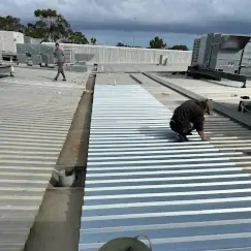Roofing City Beach metal roof installation in progress with contractor fitting new sheets on commercial building