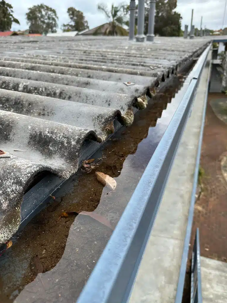 Blocked gutter filled with leaves and debris before professional gutter cleaning in Perth.
