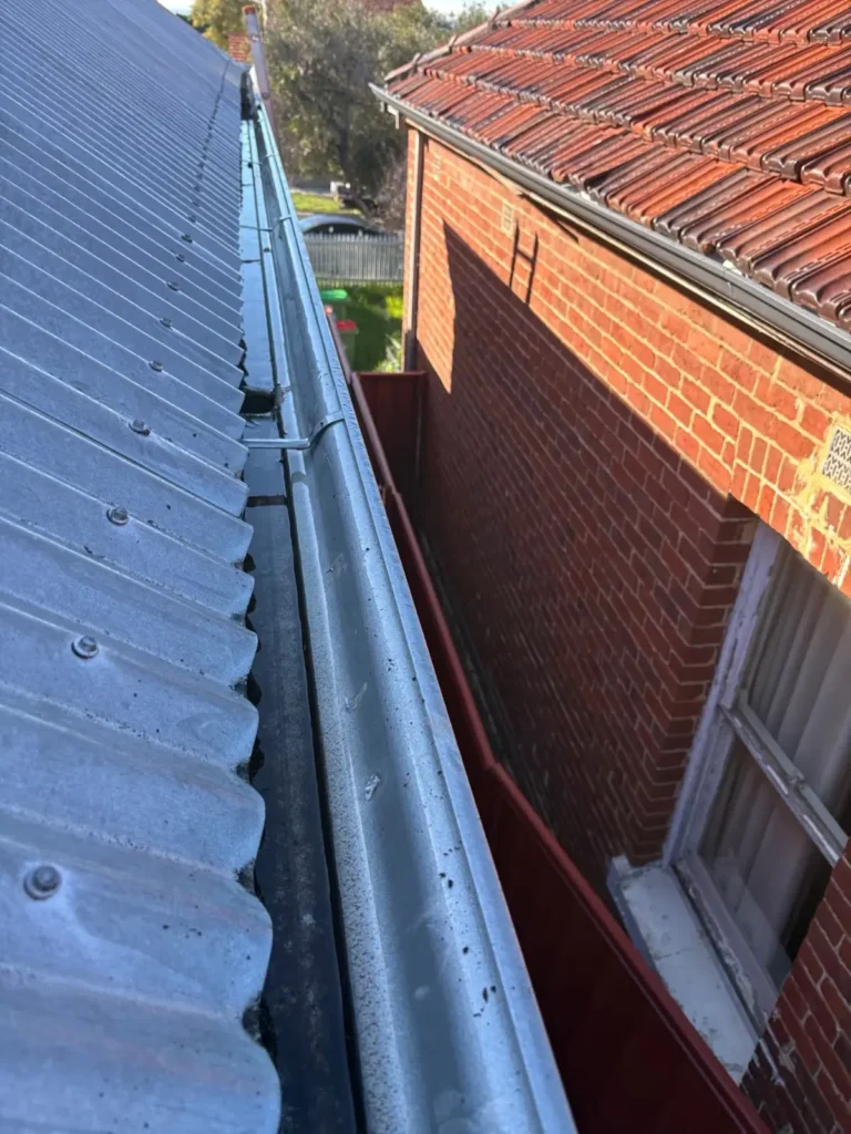Professional gutter cleaning services showing a clean metal gutter on a Perth home after debris removal and roof inspection.