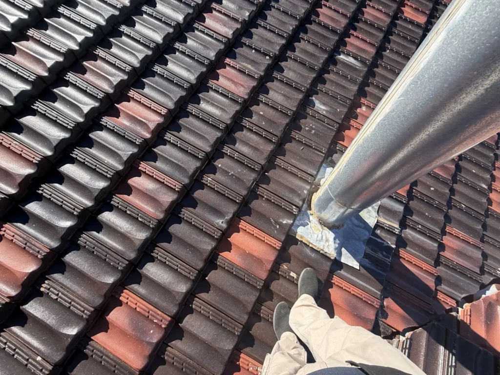 Professional roof leak inspection checking roof flashing around a metal flue.
