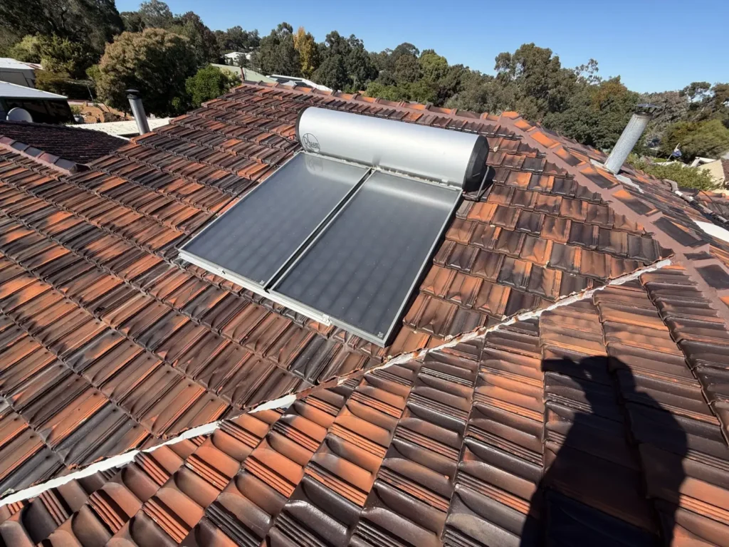 Roof leak repair inspection showing tiled roof with solar hot water system in Perth.