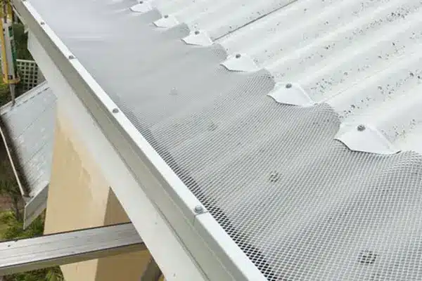 Insulmate gutter guard installed along the edge of a corrugated metal roof.