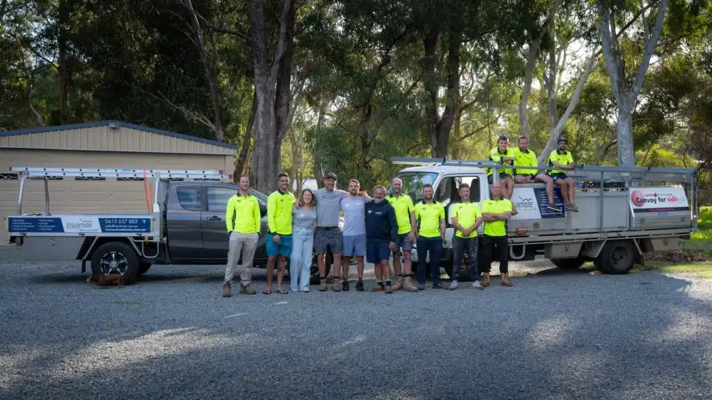 Insulmate roofing team standing in front of company service vehicles.