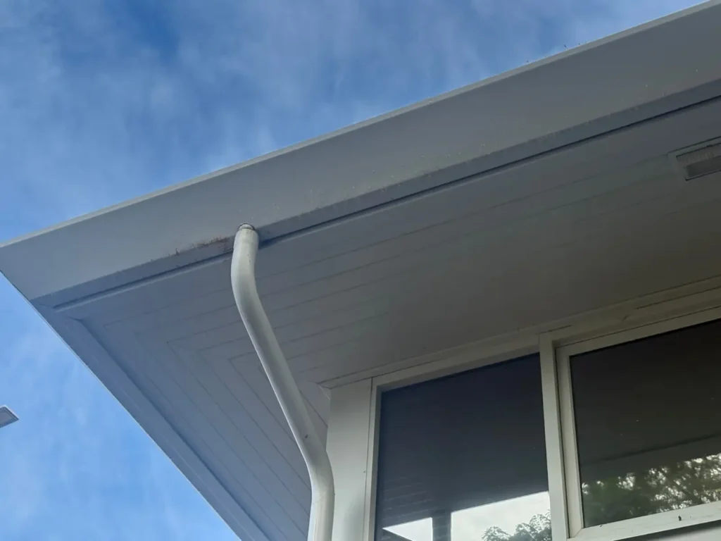 White replacement downpipe connected to roof guttering on a residential property.